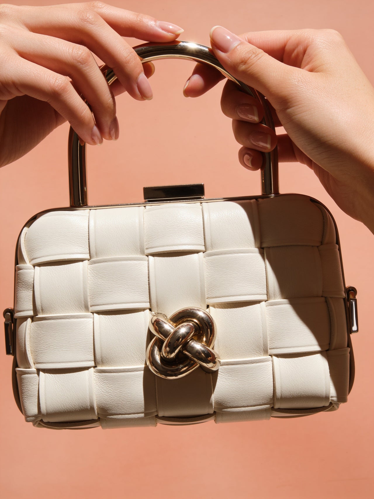 Hands holding an ivory woven mini clutch